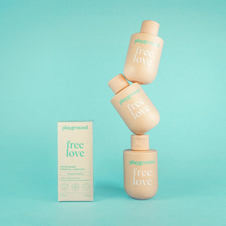 Playground Free Love Water-Based Personal Lubricant 3.7 Oz product packaging against a light blue background.