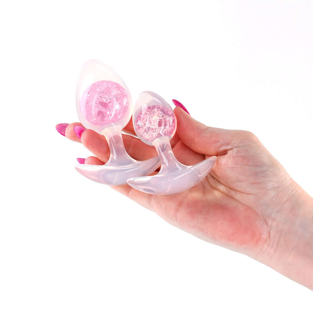 Cosmic Glams Silicone Anal Plug Kit 2pc Set Pink being held in a hand, showcasing their smooth and flexible design.