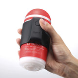 A hand holding the Tenga Cup Vibrator with a red and black design, showcasing its compact size and easy-to-use button.