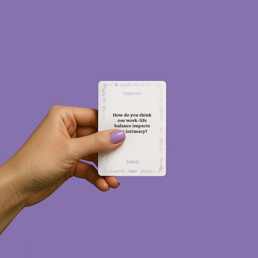 Person holding a card from the Biird x Jouissance Club Together Couples Card Game on a lavender background.
