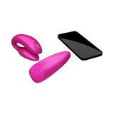 We-Vibe Chorus Couples Vibrator Cosmic Pink next to a smartphone, showcasing its innovative design and features.