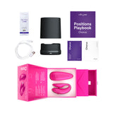 We-Vibe Chorus Couples Vibrator Cosmic Pink with accessories including lube, positions playbook, and charging cable.