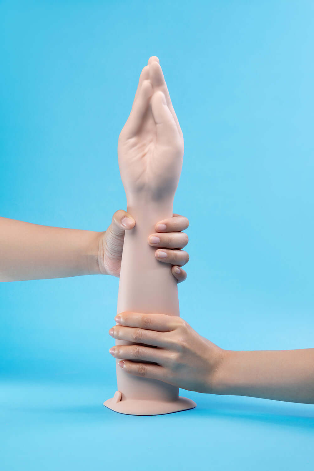 b-Vibe Silicone Hand Fisting Dildo displayed with hands gripping its lifelike arm against a blue background.