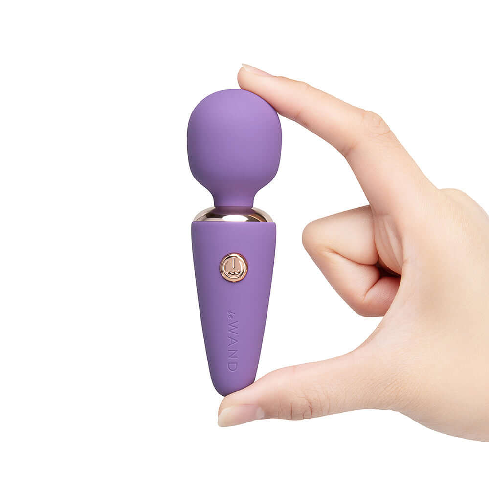 Le Wand Mini Micro Wand Massager Violet held in hand showing its sleek design and compact size.