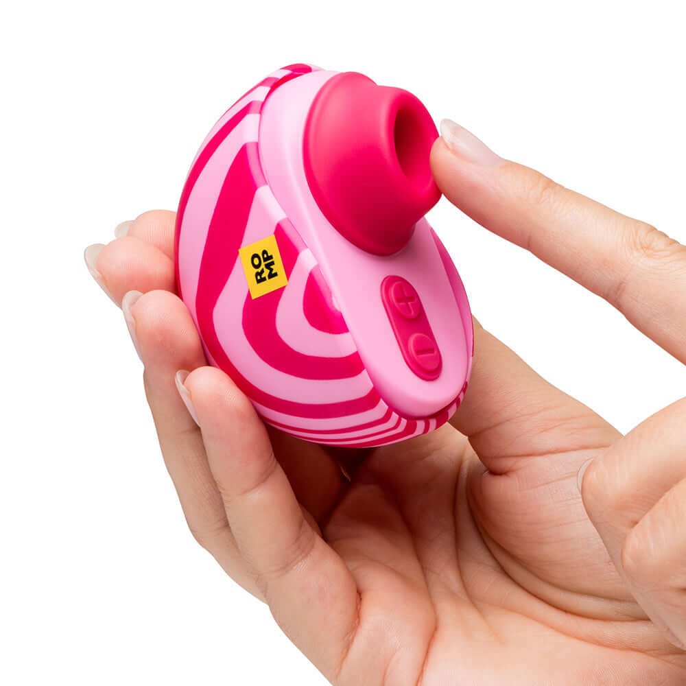 ROMP Spin Travel Rechargeable Clitoral Stimulator held in hand, featuring suction tip and control buttons.