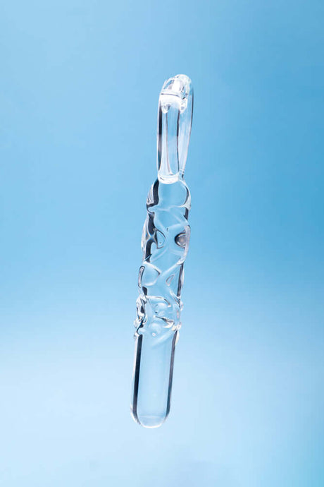 Clarity Heras Caress Glass Dildo hanging against a blue background, showcasing its elegant design and craftsmanship.