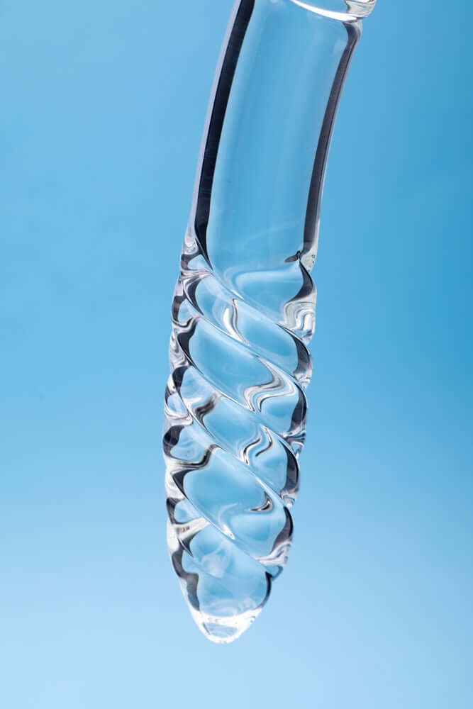 Clarity Celestial Desire Glass Dildo with a twisted design against a blue background.