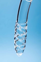 Clarity Celestial Desire Glass Dildo with a twisted design against a blue background.