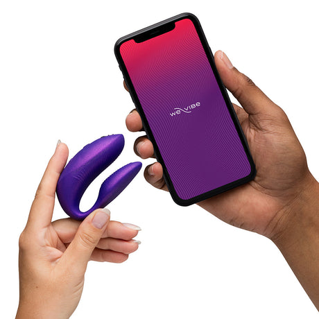 Person holding the We-Vibe Chorus Pro Cosmic Purple and a smartphone with the We-Vibe app.