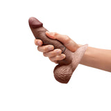 b-Vibe Slipskin Realistic Silicone Dildo 6 inch Girthy Brown held in hand showcasing its realistic design and texture.