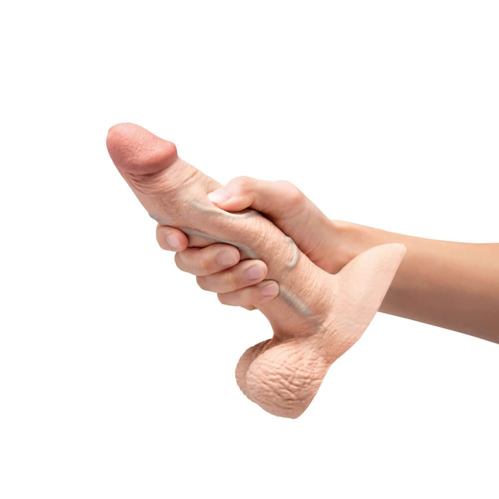 b-Vibe Slipskin Realistic Silicone Dildo 7 inch Girthy Cream held in hand to showcase its lifelike design.