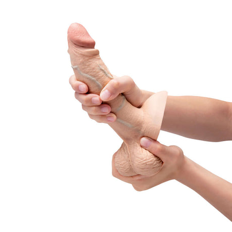 b-Vibe Slipskin Realistic Silicone Dildo 7 inch Girthy Cream being held and squeezed for realistic sensations
