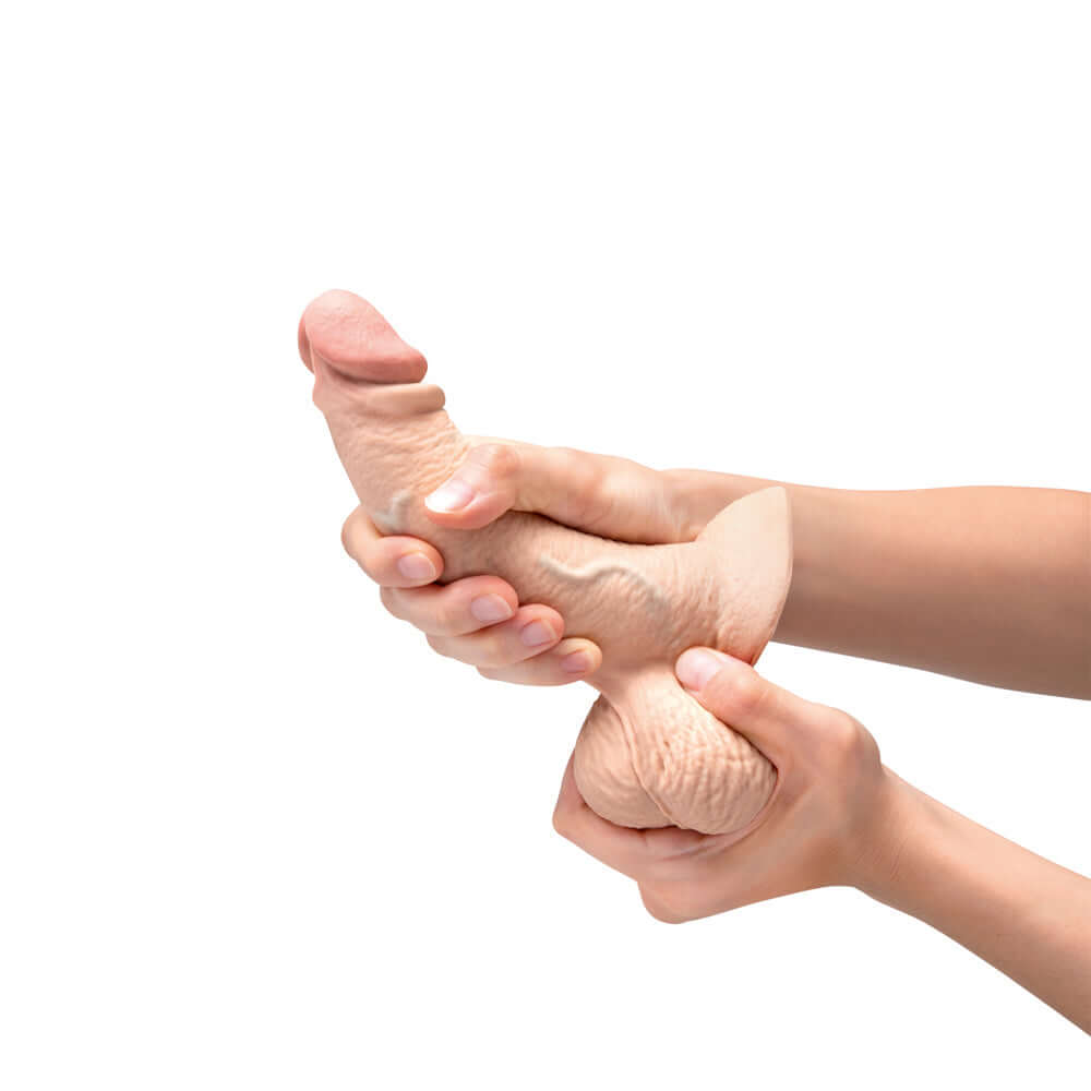 b-Vibe Slipskin Realistic Silicone Dildo 6.5 inch Curved Cream held in hands demonstrating its lifelike texture.