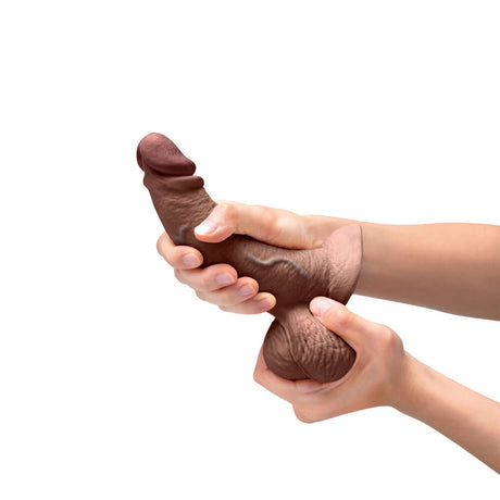 b-Vibe Slipskin Realistic Silicone Dildo 6.5 inch Curved Brown held in hands for demonstration