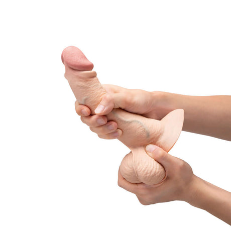 b-Vibe Slipskin Realistic Silicone Dildo 8 inch Curved Cream being held and squeezed in hands.
