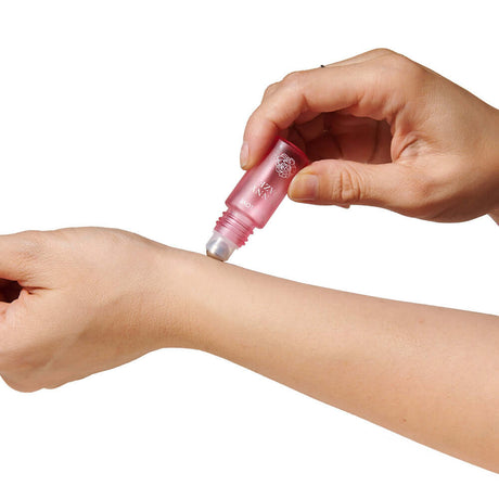 Applying Eye of Love Pheromone Perfume Roll-On Set on the wrist for an alluring fragrance experience.