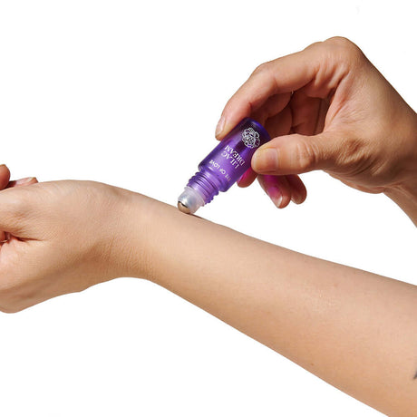 Applying Eye of Love Pheromone Perfume Roll-On Set on wrist for fragrance enhancement.