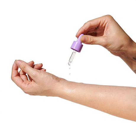 Applying Eye of Love Pheromone Perfume Oil 0.67 Oz Dropper Lilac Dream to the wrist with a dropper.