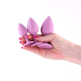 Hand holding INYA Triple Ace Plug Kit Blush with three silicone anal plugs for different experience levels.