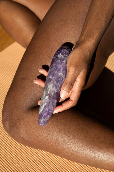Chakrubs Amethyst Original Wand held by a person, showcasing its luxurious amethyst crystal design on a yoga mat.