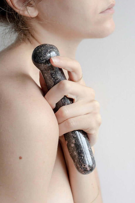 Chakrubs Anahata Curve Rhodonite Wand held close to the body, emphasizing its graceful curve and smooth texture.