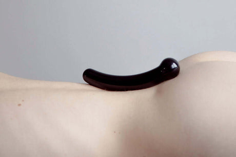 Chakrubs Xaga Curve Obsidian Wand resting on skin, showcasing its smooth design and healing properties.