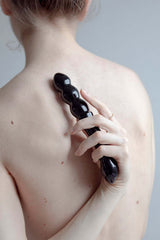 Person using Chakrubs Xaga Viper Obsidian Wand on their back for sensual pleasure and healing.