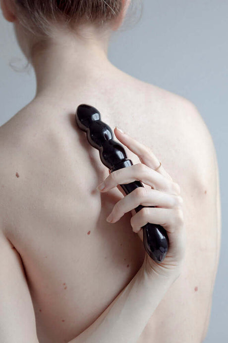 Person using Chakrubs Xaga Viper Obsidian Wand on their back for sensual pleasure and healing.