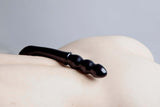 Chakrubs Xaga Viper Obsidian Wand resting on skin, showcasing its unique curvature and ridged design.