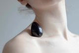 Chakrubs Xaga Yoni Egg Obsidian non-drilled resting on skin for body and spirit wellness.