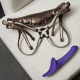 Strap-on-me Multi Orgasm Dildo Medium Purple with harness on a textured surface.