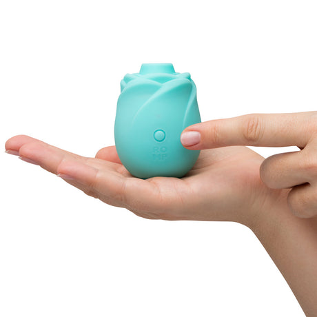 Romp Glow Air Suction Rose Massager held in a hand, showcasing its rose-inspired design and silicone material.