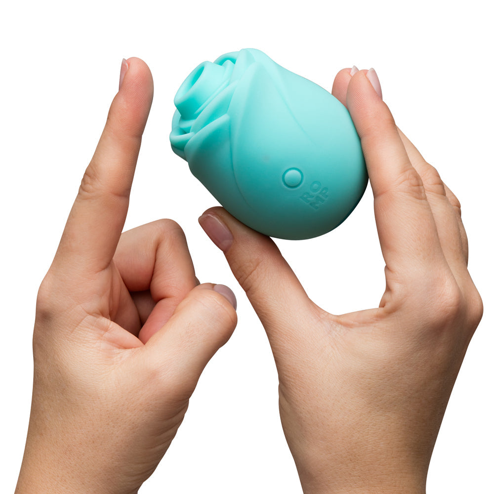 Romp Glow Air Suction Rose Massager in soft silicone held by two hands, showcasing its elegant design and functionality.