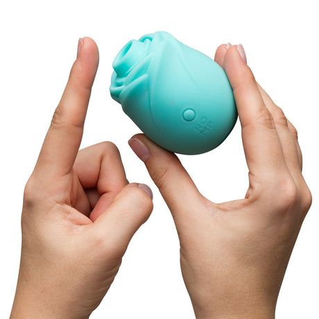 Romp Glow Air Suction Rose Massager in soft silicone held by two hands, showcasing its elegant design and functionality.