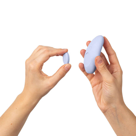 Person holding the Dame Lay Panty Vibrator With Remote Control and a remote, showcasing its compact design.