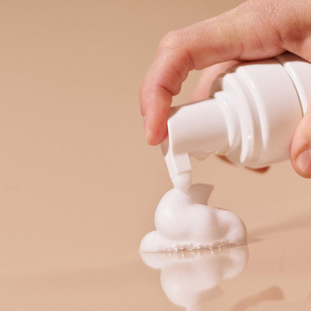 Hand dispensing foam from the bottle of Sex Au Naturel Prebiotic Intimate Wash Gentle Foam.