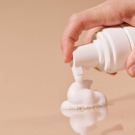 Hand dispensing foam from the bottle of Sex Au Naturel Prebiotic Intimate Wash Gentle Foam.