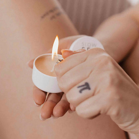 Bijoux Indiscrets Slow Sex Massage Candle being lit, ready for a sensual massage experience.