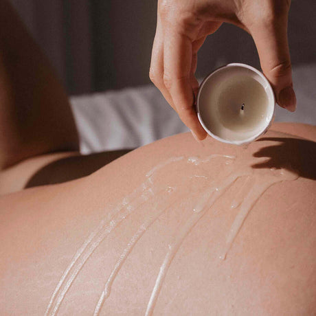 Bijoux Indiscrets Slow Sex Massage Candle being poured onto skin for a soothing massage experience.