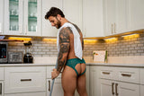 Man wearing Male Power Ripple Moon Jock Teal S/M in a modern kitchen, showcasing stylish lace design.