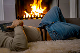 Male Power Eco Cozy Cutout Thong Green S/M worn by a man relaxing by the fireplace while reading a book.