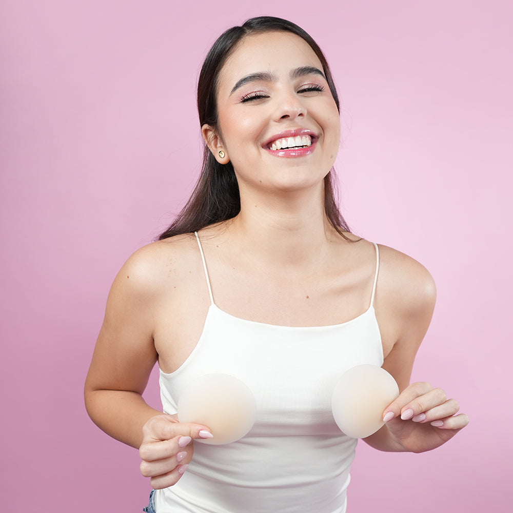 UVA Circular Nipple Covers Cocoa model smiling while holding the covers against her skin.
