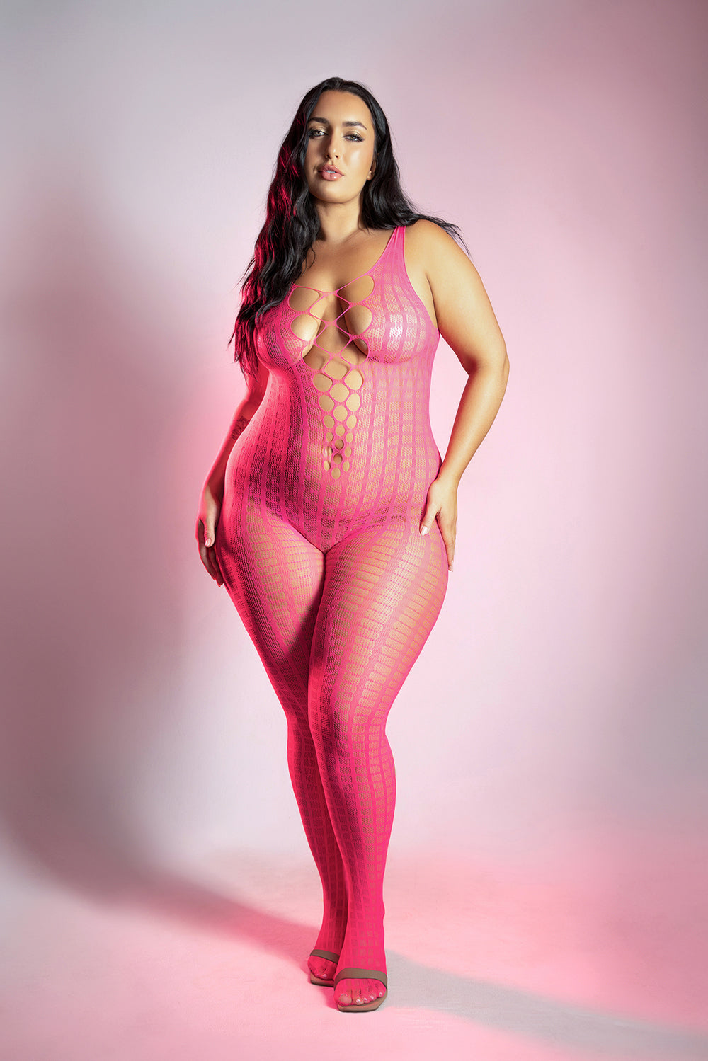 Model wearing Fantasy Lingerie Glow Turn Up Bodystocking Queen Size in vibrant neon pink under soft lighting.