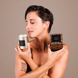 Je Joue Luxury Leather Massage Candle 160g held by a woman enjoying its aroma, showcasing luxury and relaxation.