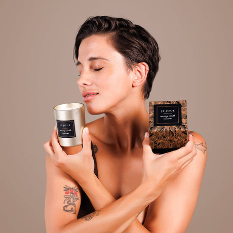 Je Joue Luxury Leather Massage Candle 160g held by a woman enjoying its aroma, showcasing luxury and relaxation.