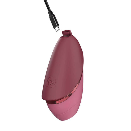 Womanizer Next Liberty Air Clitoral Massager Bordeaux with charging cable connected, sleek design in Bordeaux color.