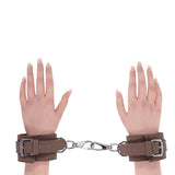Sportsheets Signature Dawn Dream Handcuffs in smooth brown silicone with silver hardware connecting two hands.