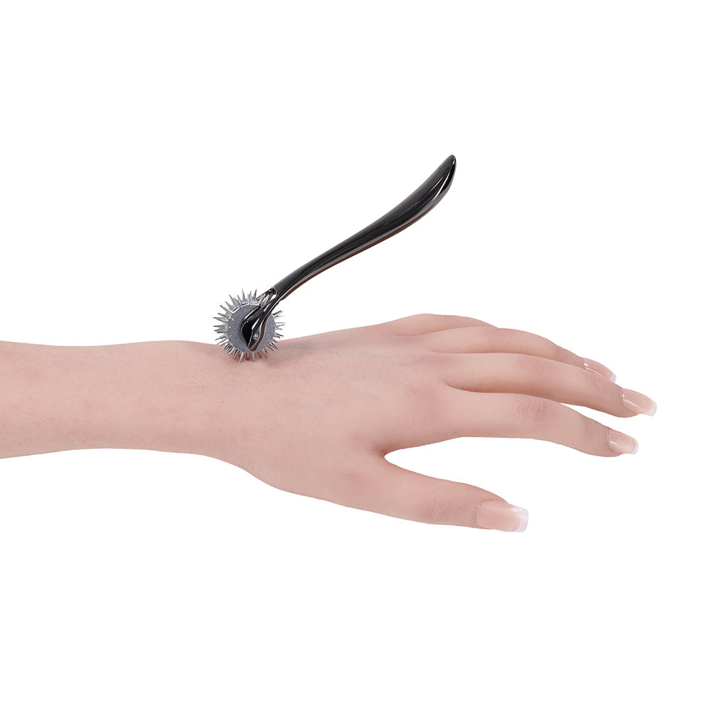 Sportsheets Signature Wartenberg Wheel gliding over a hand, enhancing sensation play experience.