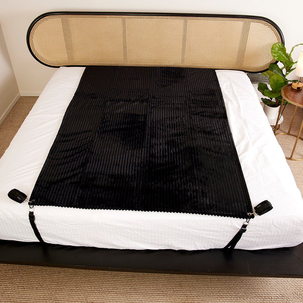 Sportsheets Signature Waterproof Blanket laid on a bed, showcasing its plush texture and waterproof features.