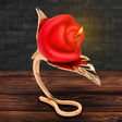 Burning Passion Rose Candle with Holder elegantly displayed on a golden leaf stand, resembling a blooming rose.